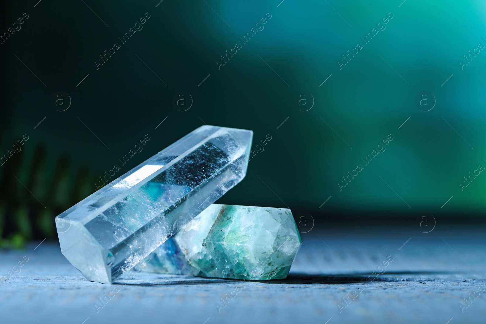 Photo of Beautiful natural gemstones on grey wooden table. Space for text