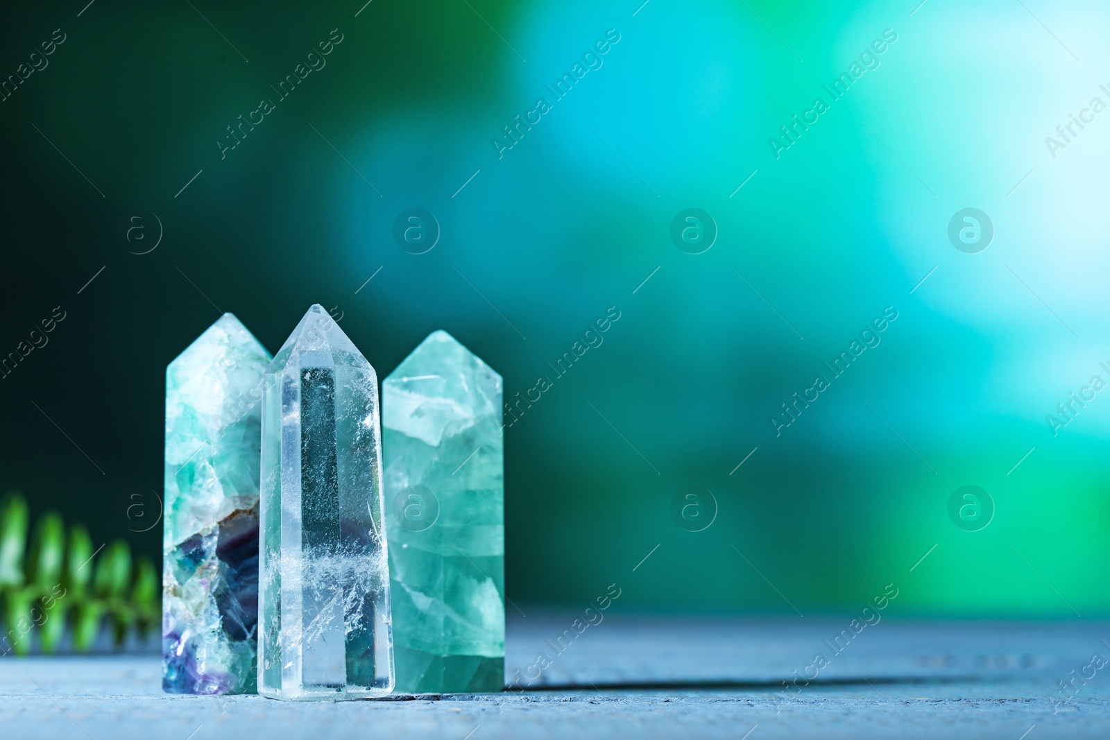 Photo of Beautiful natural gemstones on grey wooden table. Space for text