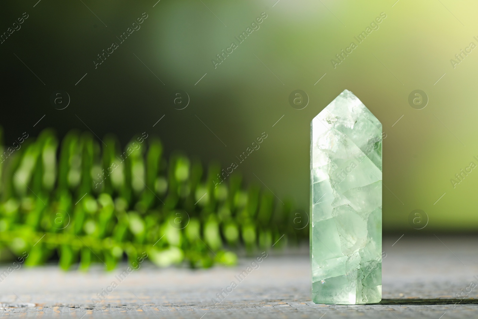 Photo of Beautiful natural gemstone on grey wooden table. Space for text