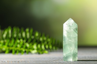 Photo of Beautiful natural gemstone on grey wooden table. Space for text