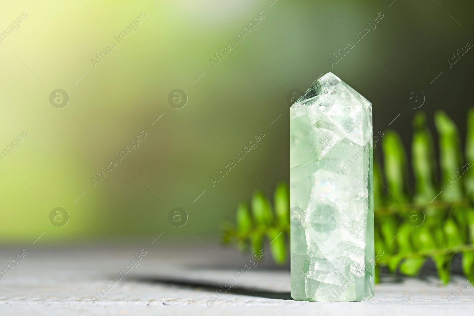 Photo of Beautiful natural gemstone on grey wooden table. Space for text