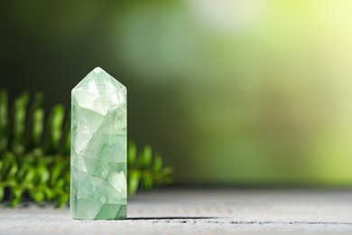 Photo of Beautiful natural gemstone on grey wooden table. Space for text