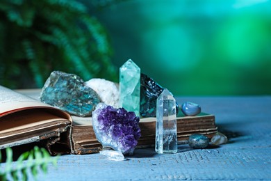 Photo of Beautiful natural gemstones and book on grey table against green background