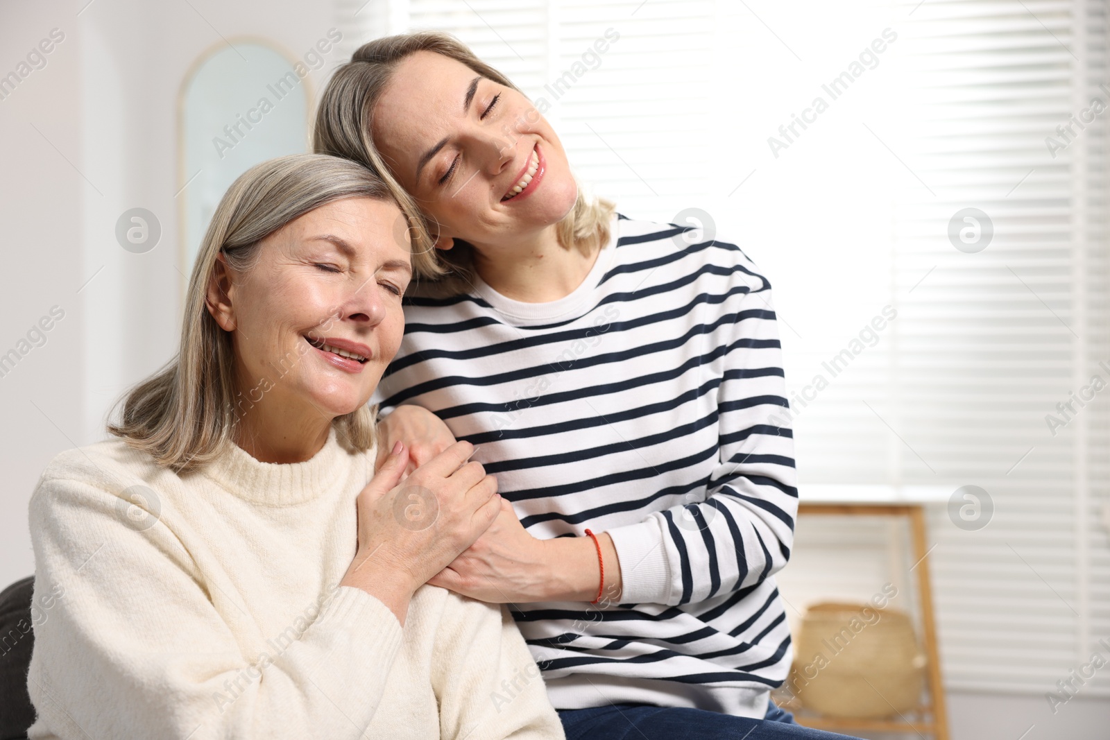 Photo of Smiling daughter and her mother at home, space for text