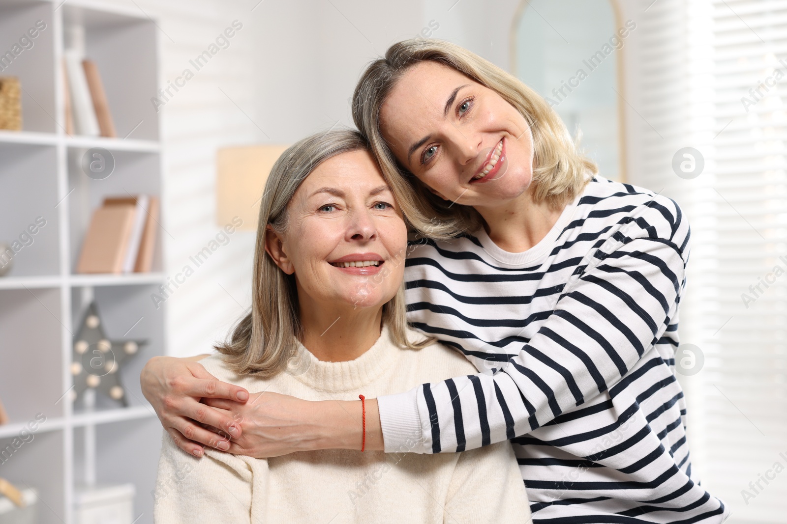 Photo of Smiling daughter hugging her mother at home