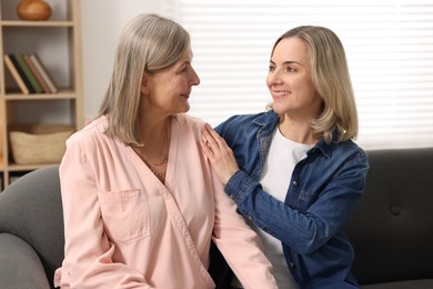 Smiling daughter and her mother on sofa at home