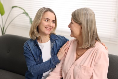 Smiling daughter and her mother on sofa at home