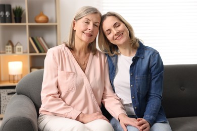 Smiling mother and her daughter on sofa at home