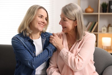 Photo of Smiling mother and her daughter on sofa at home