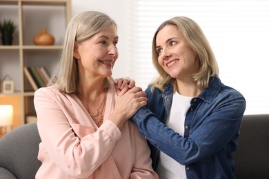 Photo of Smiling mother and her daughter on sofa at home