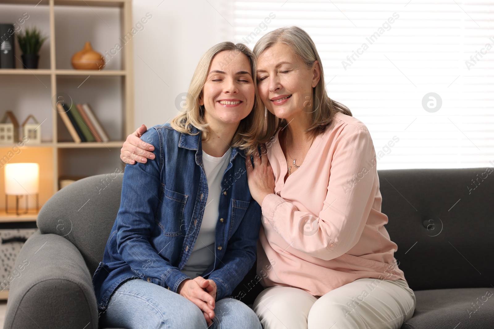 Photo of Smiling mother and her daughter on sofa at home