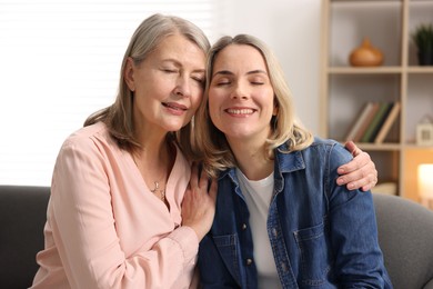 Photo of Smiling mother and her daughter on sofa at home