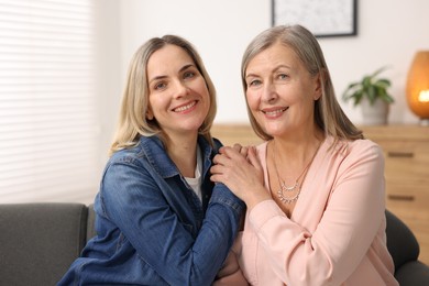 Smiling mother and her daughter on sofa at home