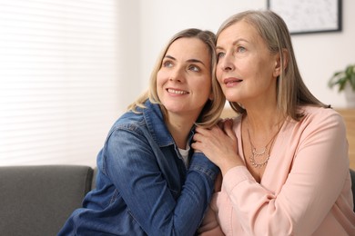 Photo of Smiling daughter and her mother on sofa at home