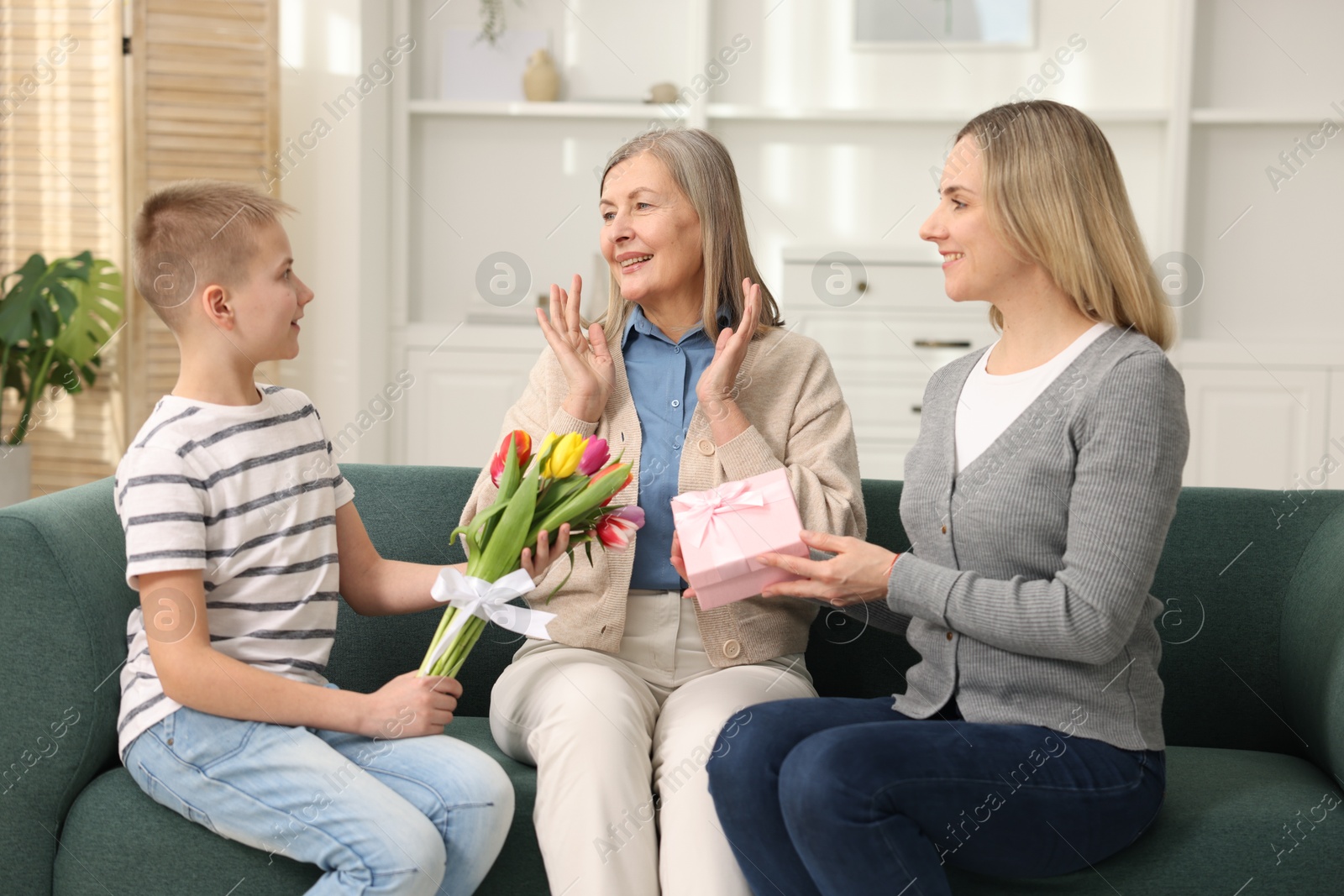 Photo of Mother and son congratulating their happy parent with Mother's Day on sofa at home