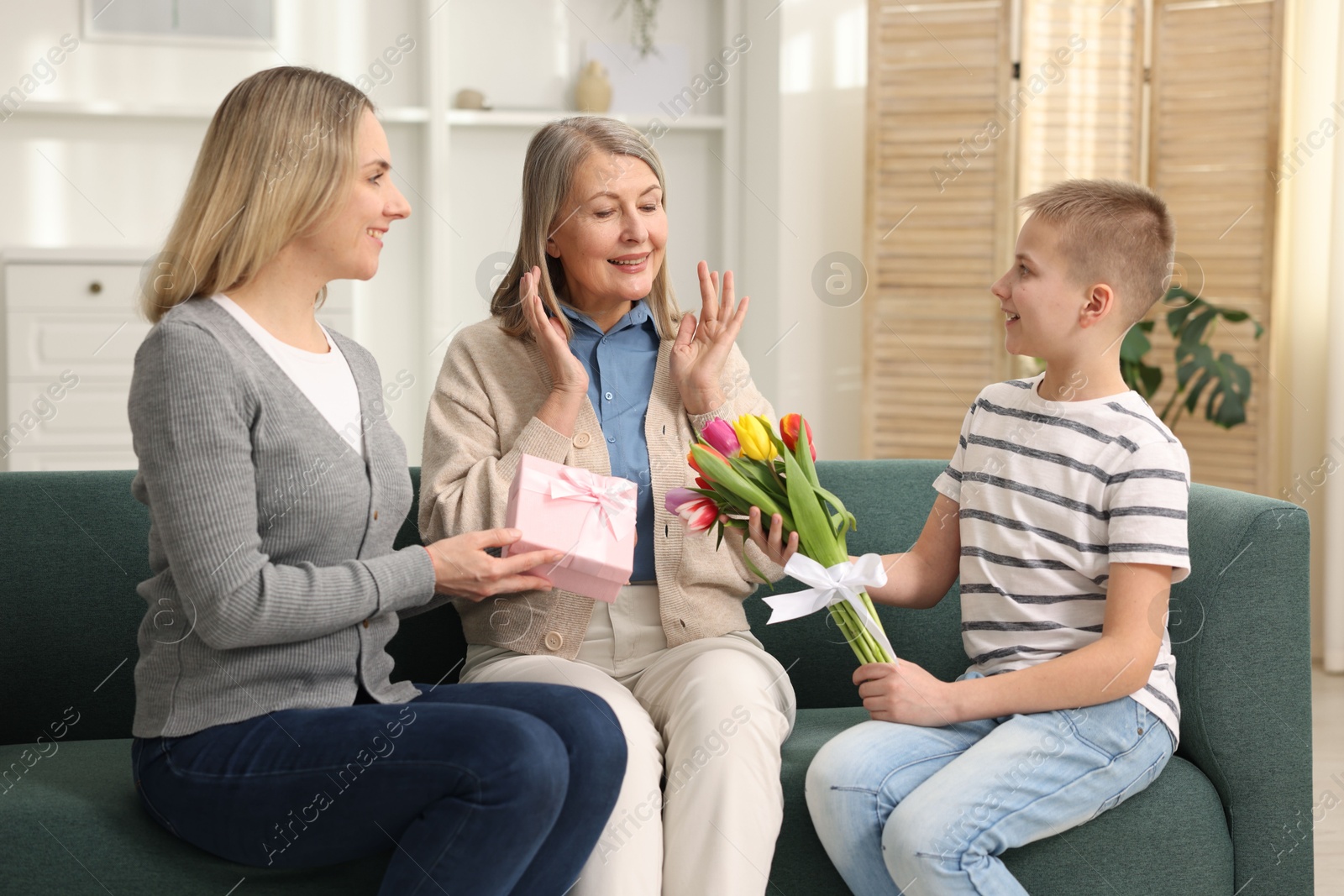 Photo of Mother and son congratulating their happy parent with Mother's Day on sofa at home