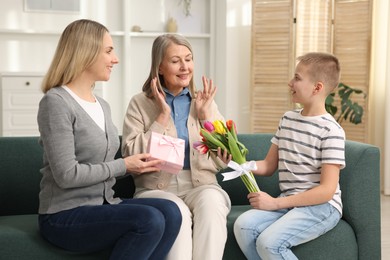 Mother and son congratulating their happy parent with Mother's Day on sofa at home