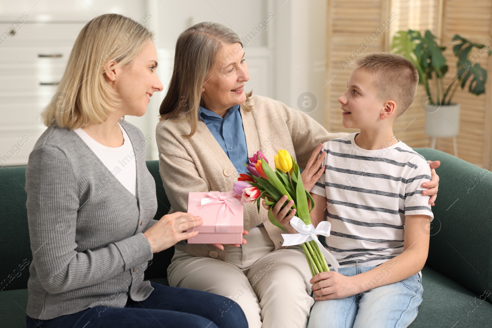 Photo of Mother and son congratulating their happy parent with Mother's Day on sofa at home