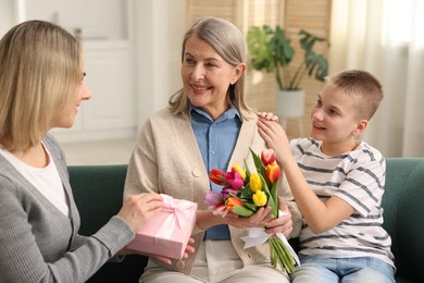 Mother and son congratulating their happy parent with Mother's Day on sofa at home