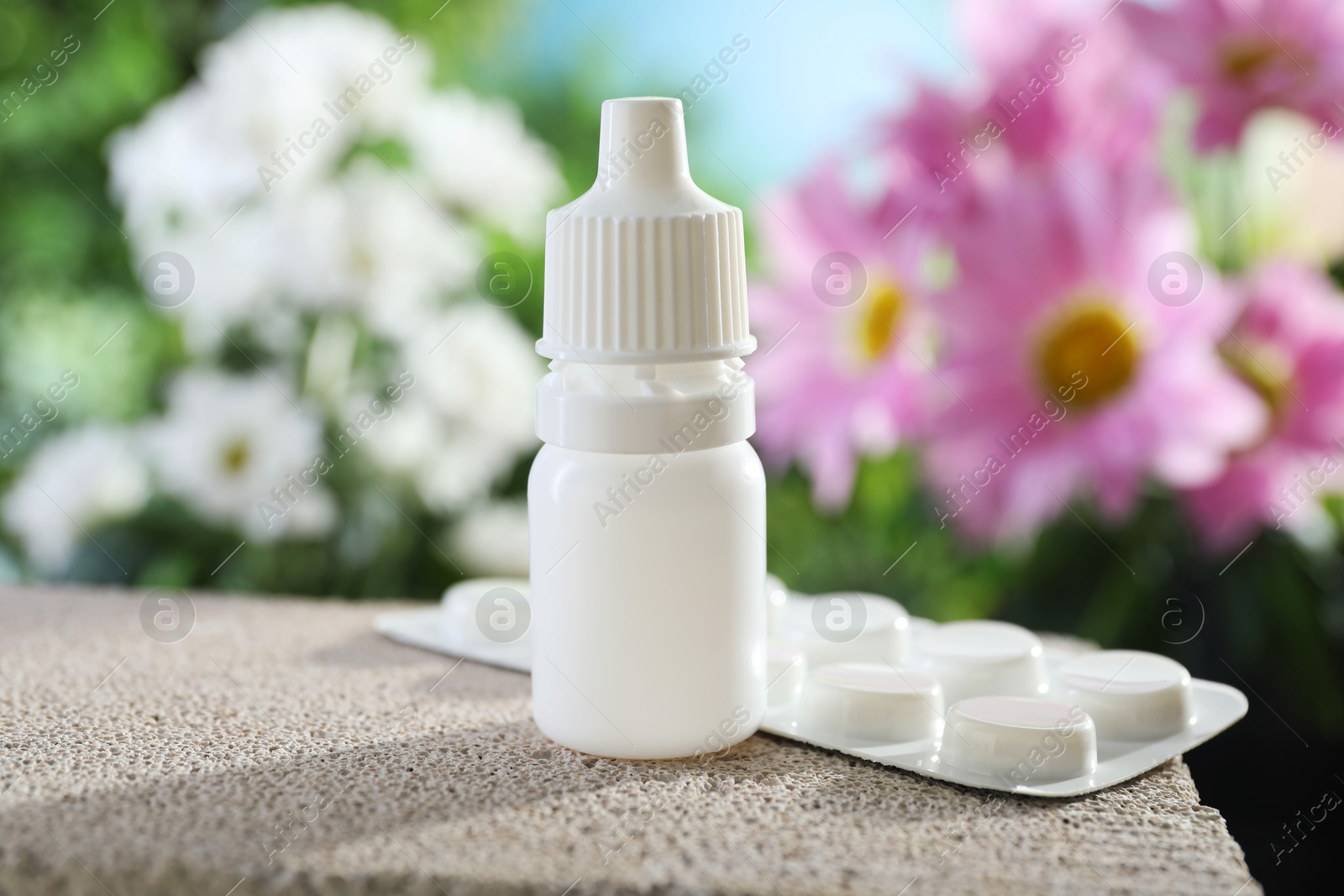 Photo of Allergy treatment. Bottle of medical drops and pills on stone against blurred background, closeup