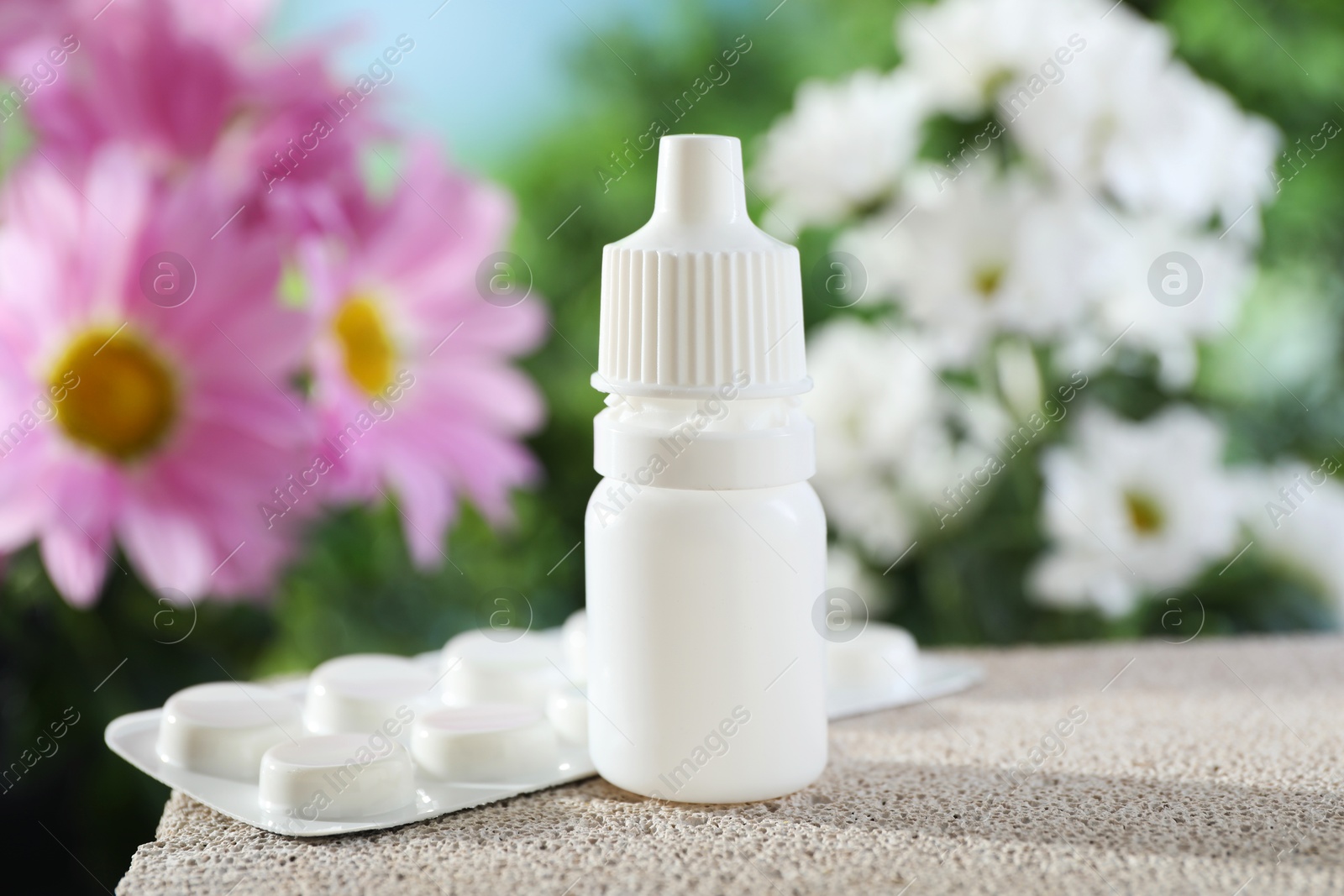 Photo of Allergy treatment. Bottle of medical drops and pills on stone against blurred background, closeup