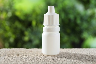 Photo of Allergy treatment. Bottle of medical drops on stone against blurred background, closeup