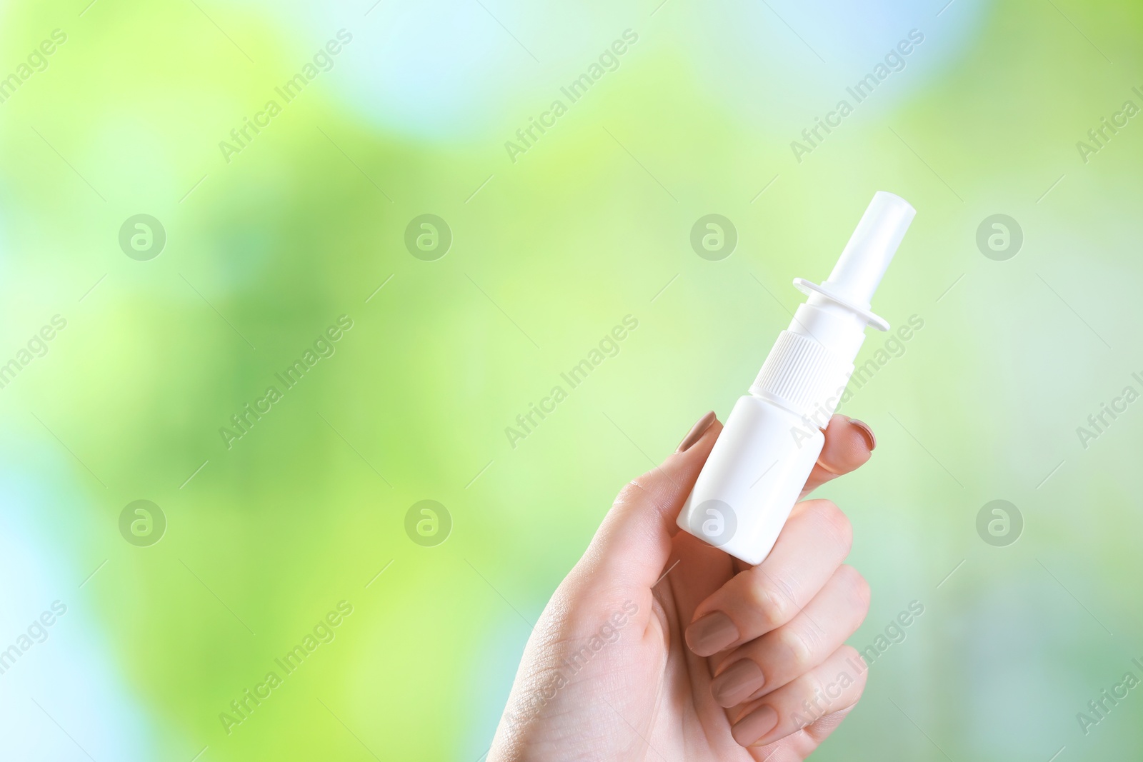 Photo of Allergy treatment. Woman with nasal spray on blurred background, closeup. Space for text