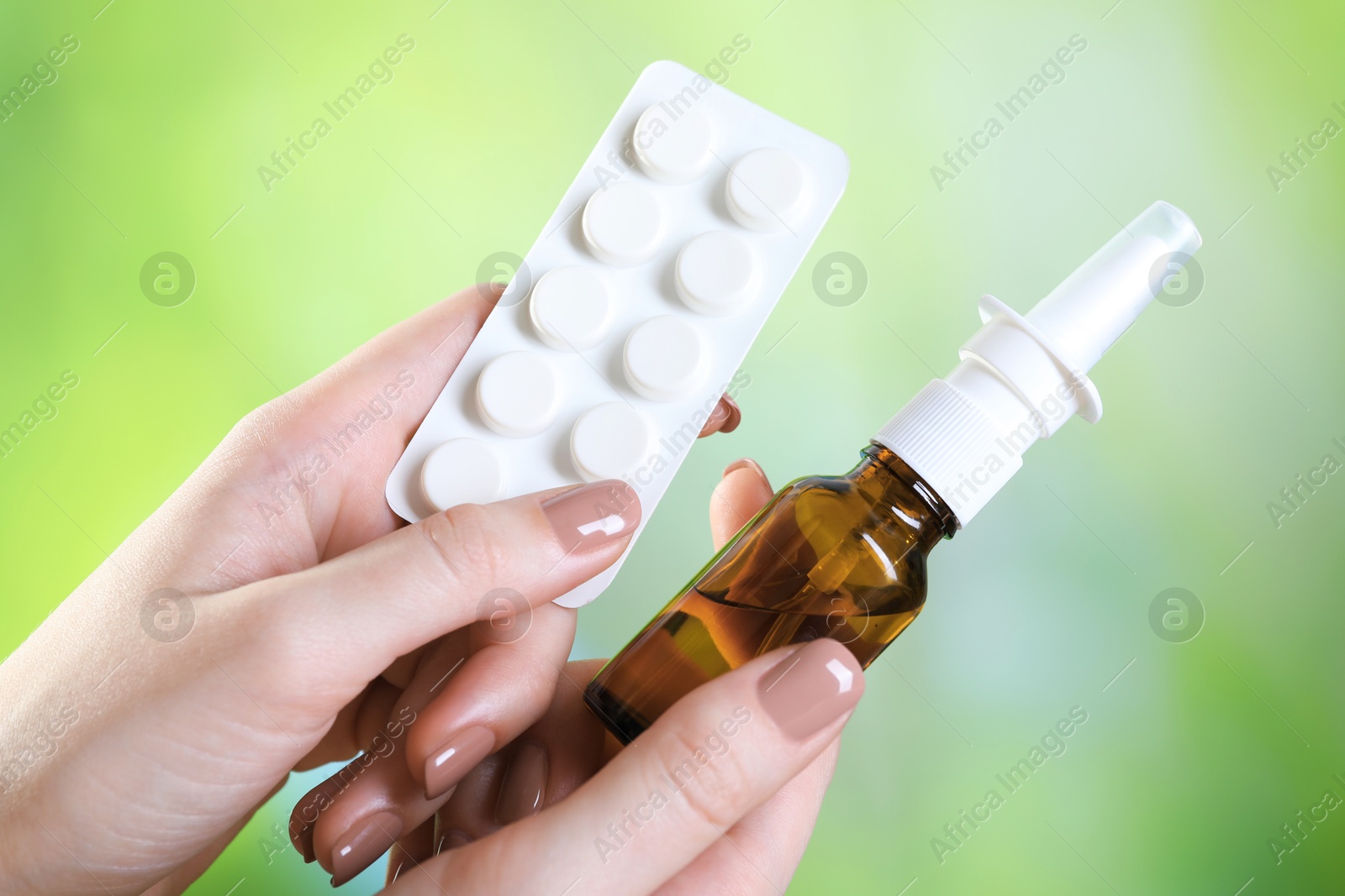 Photo of Allergy treatment. Woman with nasal spray and pills on blurred background, closeup