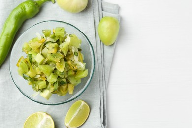 Photo of Delicious salsa (Pico de gallo) in bowl and products on white wooden table, top view. Space for text