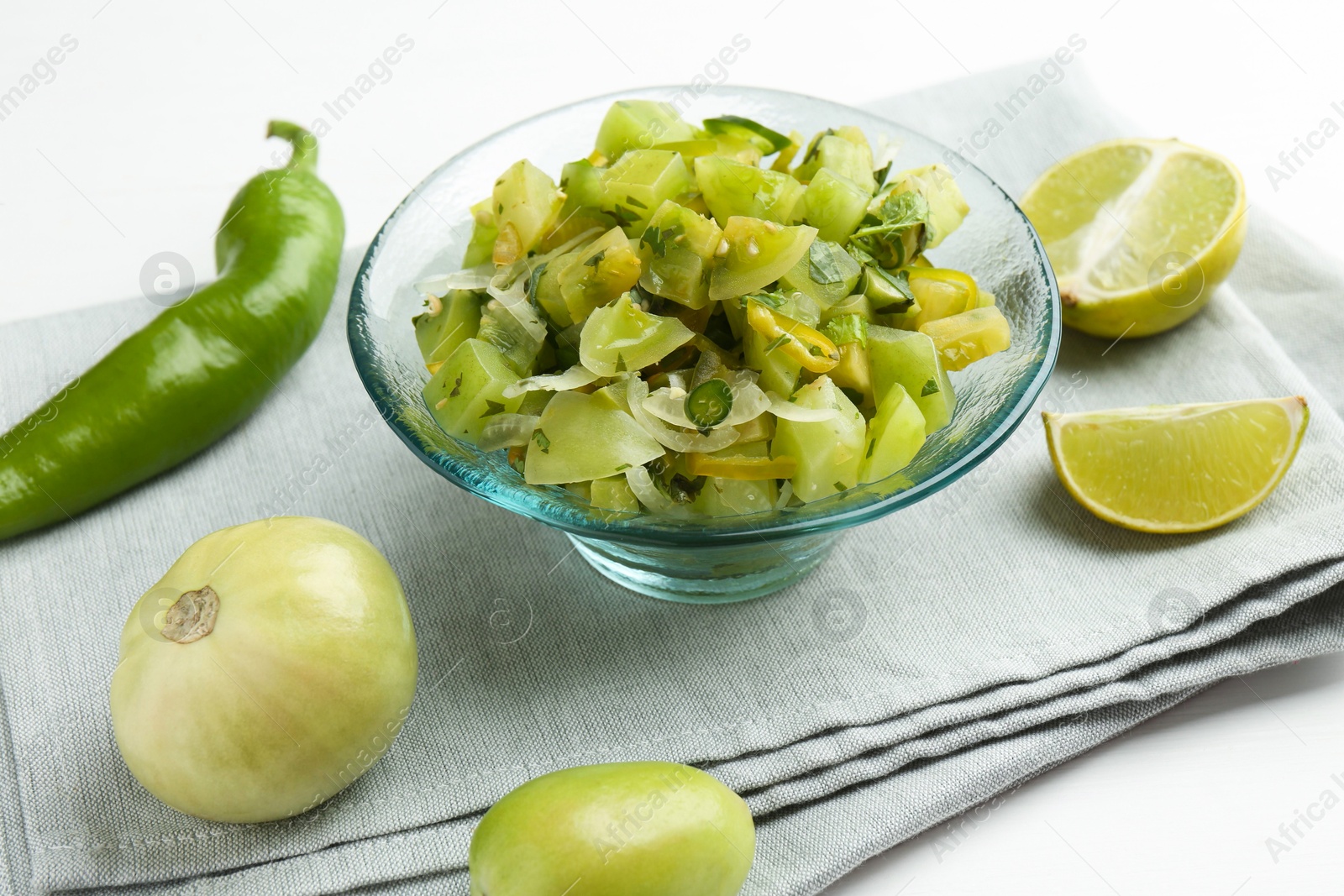 Photo of Delicious salsa (Pico de gallo) in bowl and products on white table, closeup