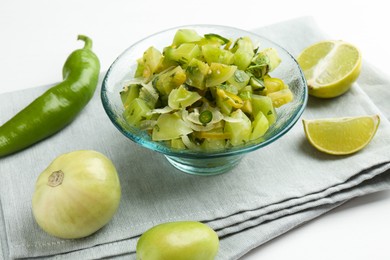 Photo of Delicious salsa (Pico de gallo) in bowl and products on white table, closeup