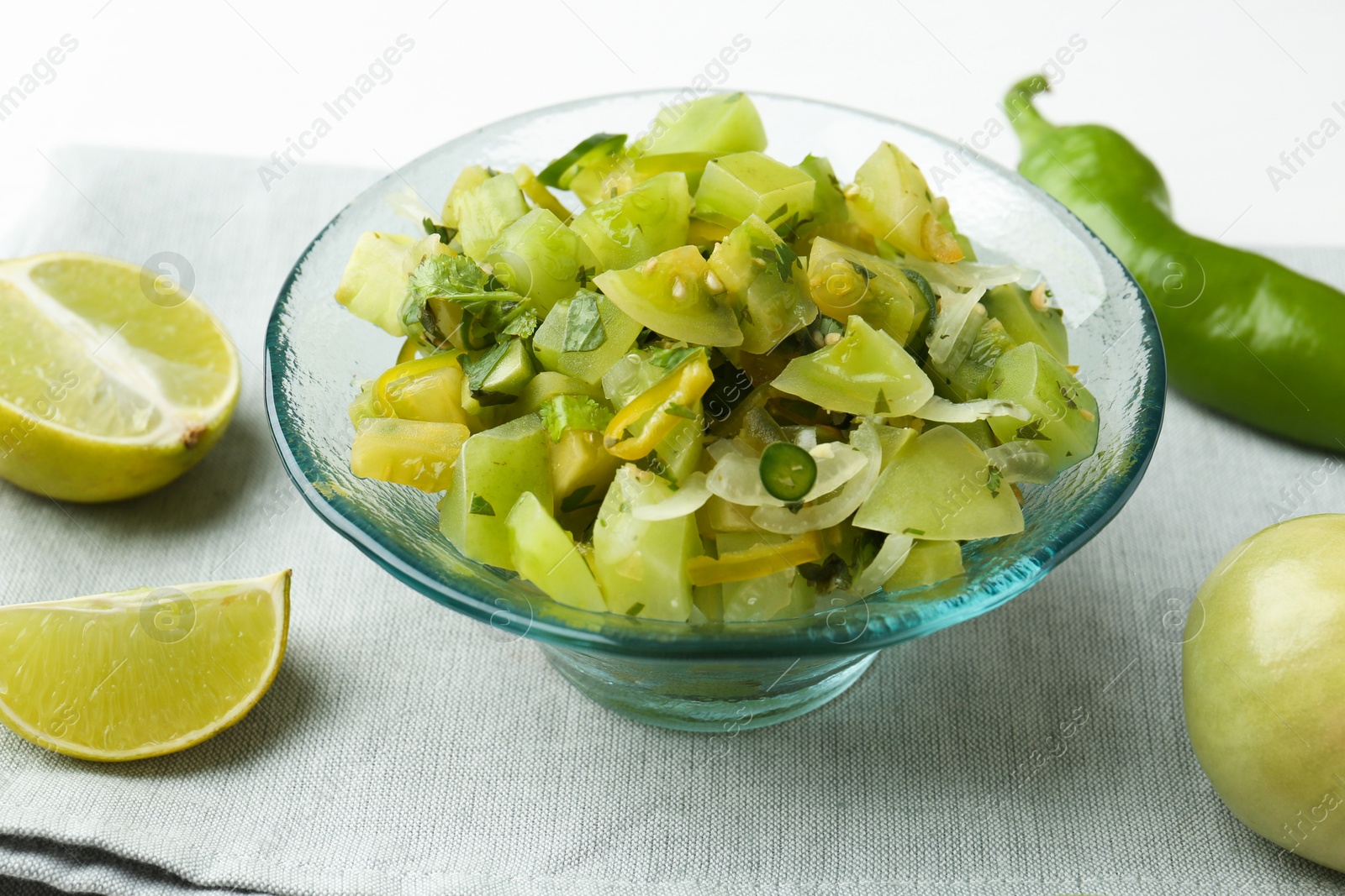 Photo of Delicious salsa (Pico de gallo) in bowl and products on white table, closeup