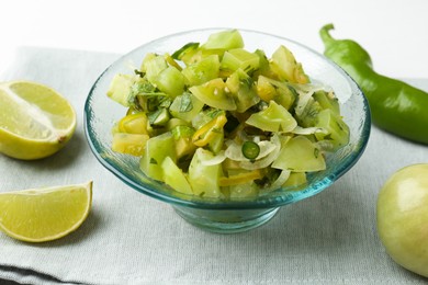 Photo of Delicious salsa (Pico de gallo) in bowl and products on white table, closeup