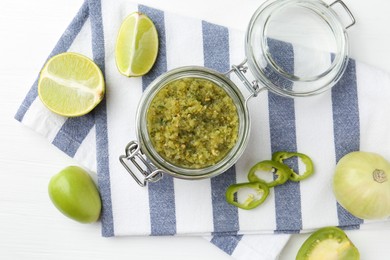 Photo of Delicious salsa sauce in jar and products on white wooden table, flat lay