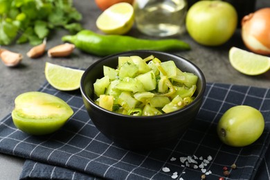 Photo of Delicious salsa (Pico de gallo) in bowl and products on grey table, closeup