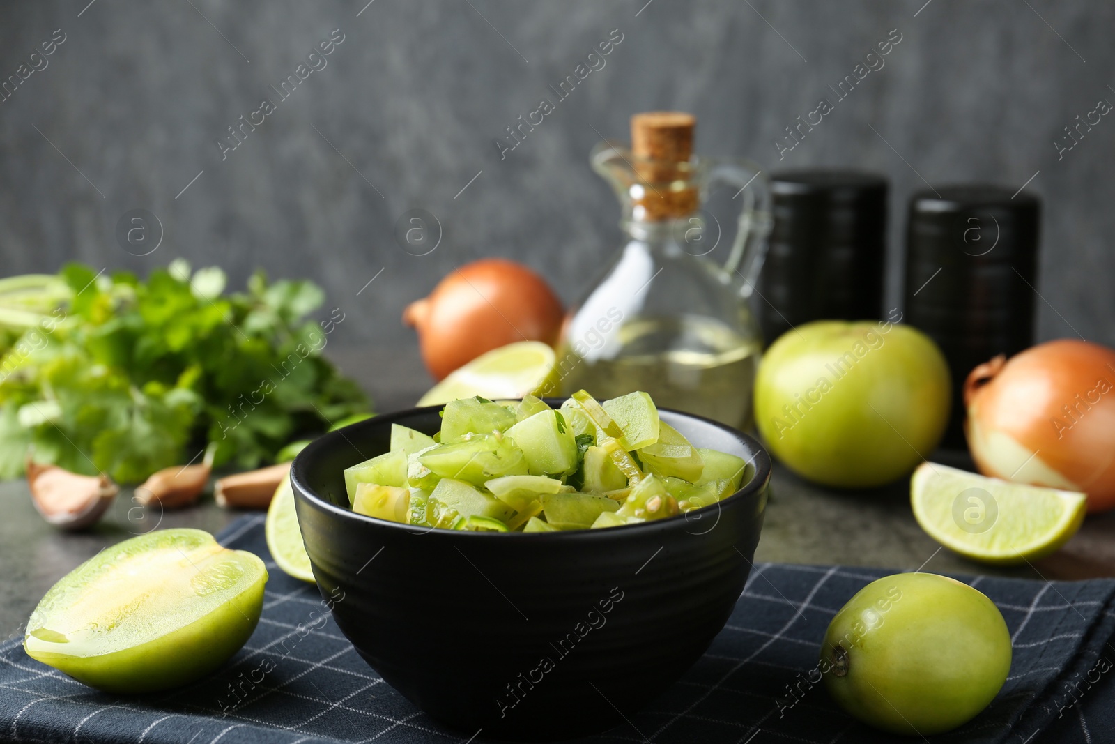 Photo of Delicious salsa (Pico de gallo) in bowl and products on grey table, closeup