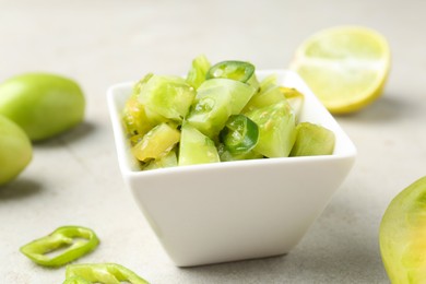 Photo of Delicious salsa (Pico de gallo) in bowl and products on light textured table, closeup