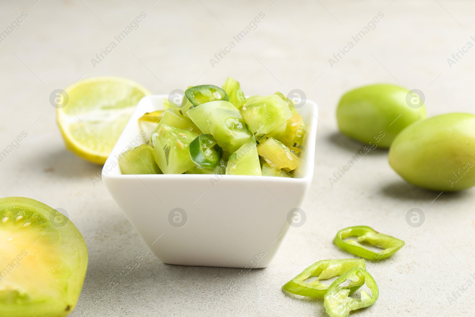 Photo of Delicious salsa (Pico de gallo) in bowl and products on light textured table, closeup