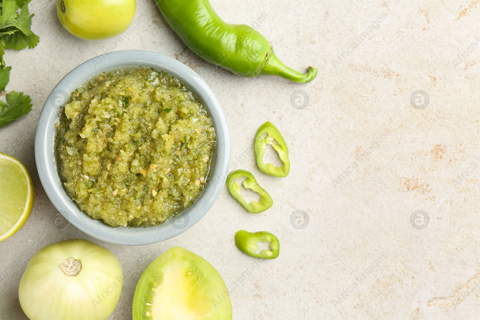 Photo of Delicious salsa sauce in bowl and ingredients on light textured table, flat lay. Space for text