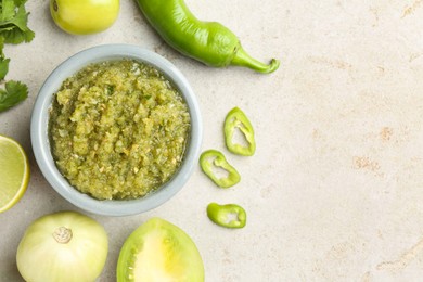 Photo of Delicious salsa sauce in bowl and ingredients on light textured table, flat lay. Space for text