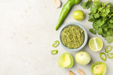 Photo of Delicious salsa sauce in bowl and ingredients on light textured table, flat lay. Space for text