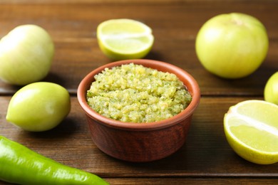 Photo of Delicious salsa sauce in bowl and products on wooden table, closeup