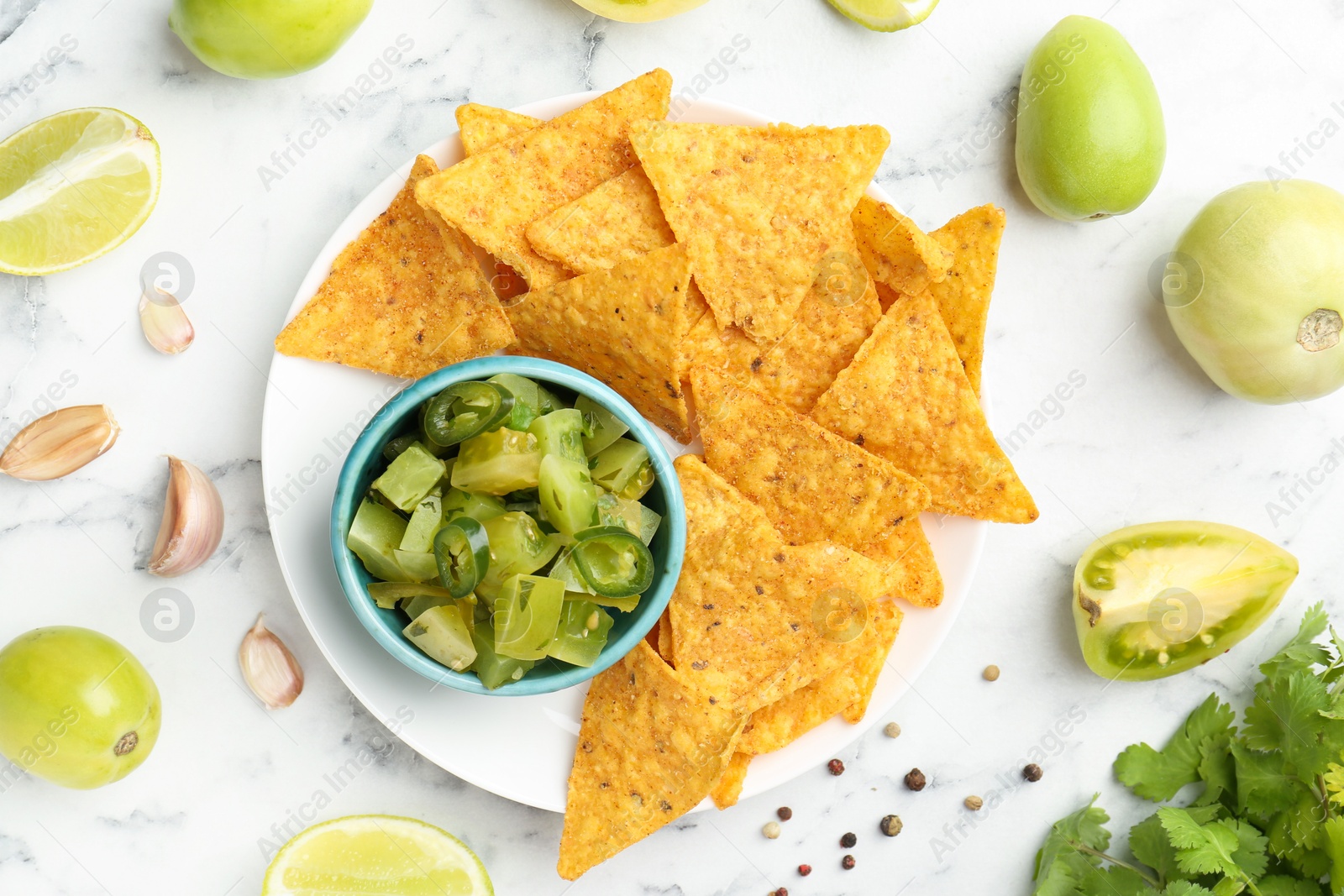 Photo of Delicious salsa with nachos on white marble table, flat lay