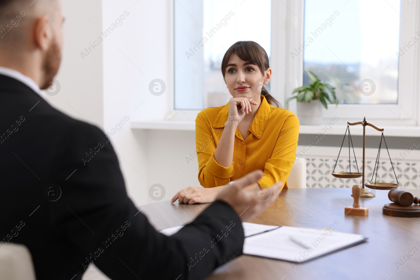 Photo of Woman having meeting with professional lawyer at wooden desk indoors