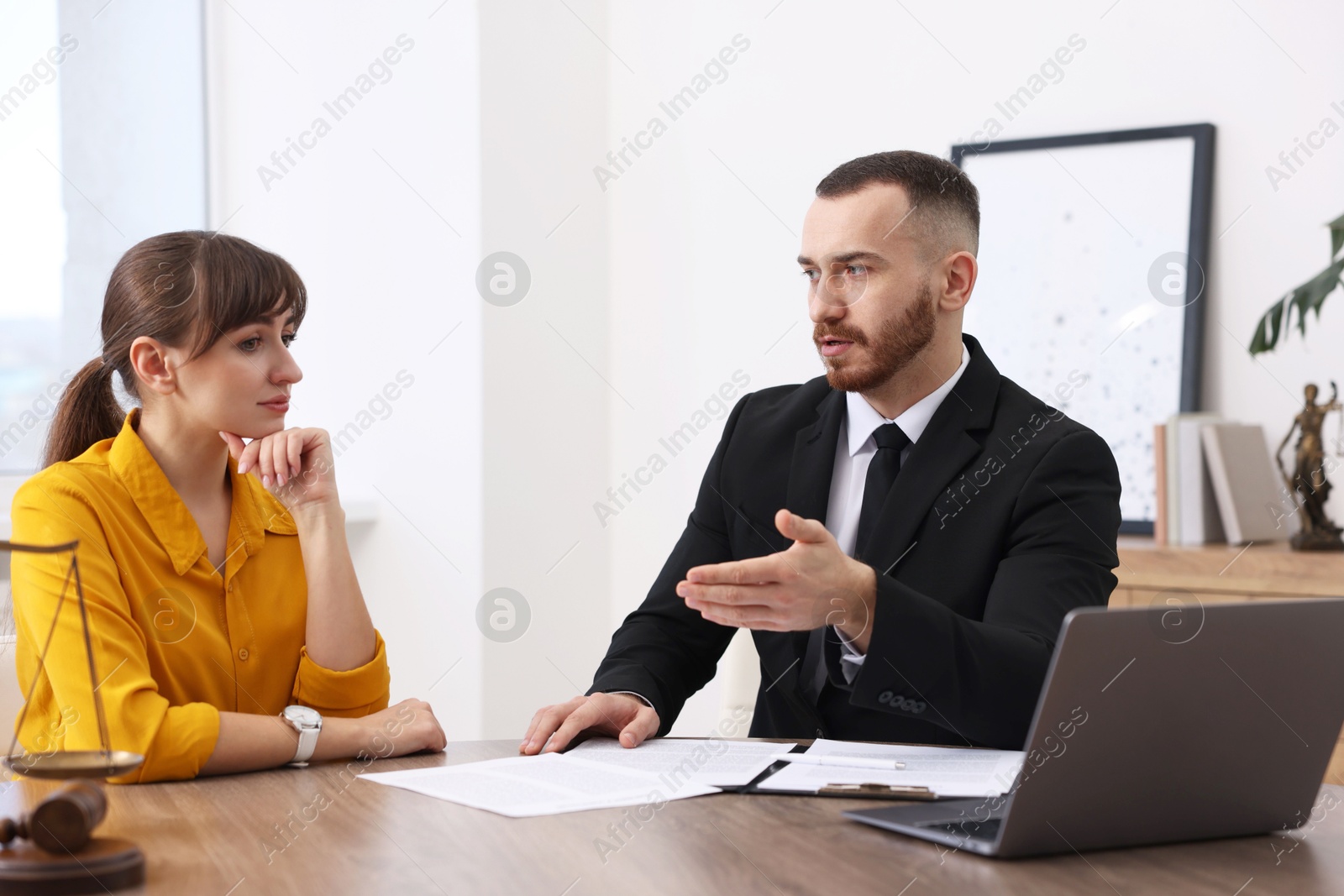 Photo of Woman having meeting with professional lawyer at wooden desk indoors