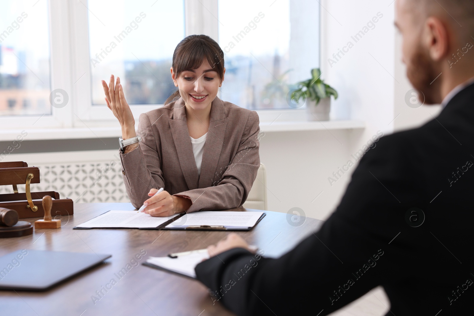 Photo of Man having meeting with professional notary at wooden desk indoors