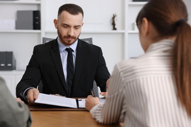 Man and woman having meeting with professional lawyer at wooden desk indoors