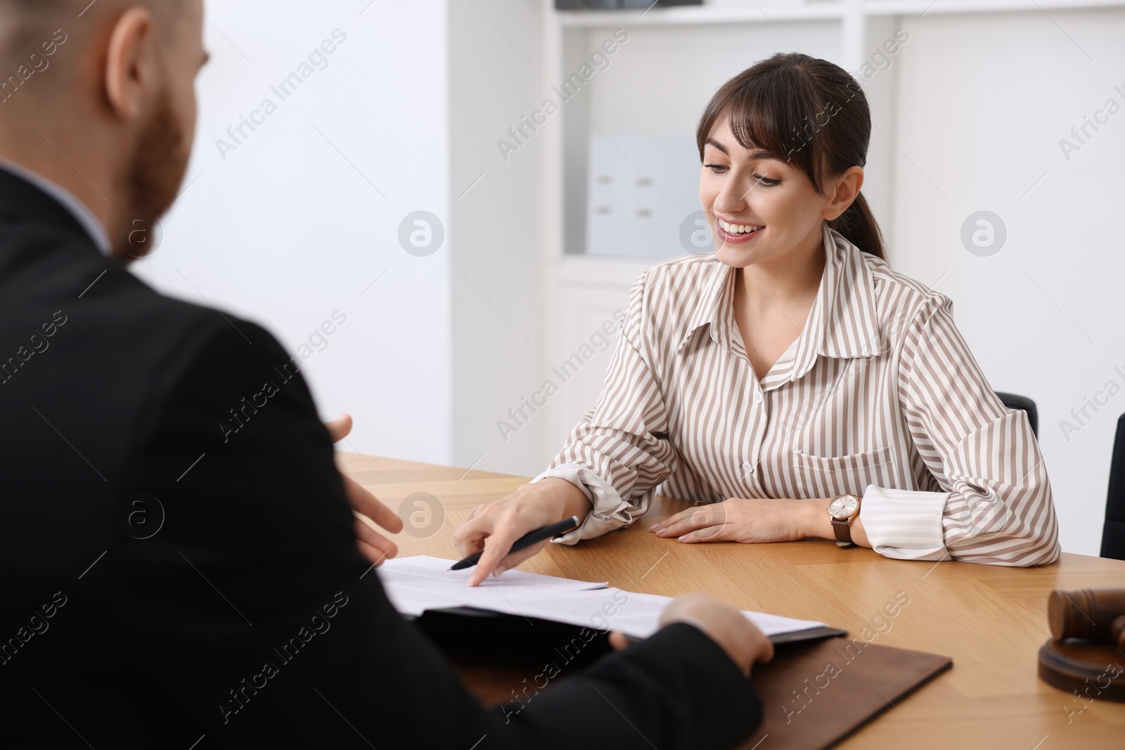 Photo of Woman having meeting with professional notary at wooden desk indoors