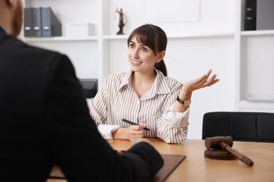 Photo of Woman having meeting with professional notary at wooden desk indoors