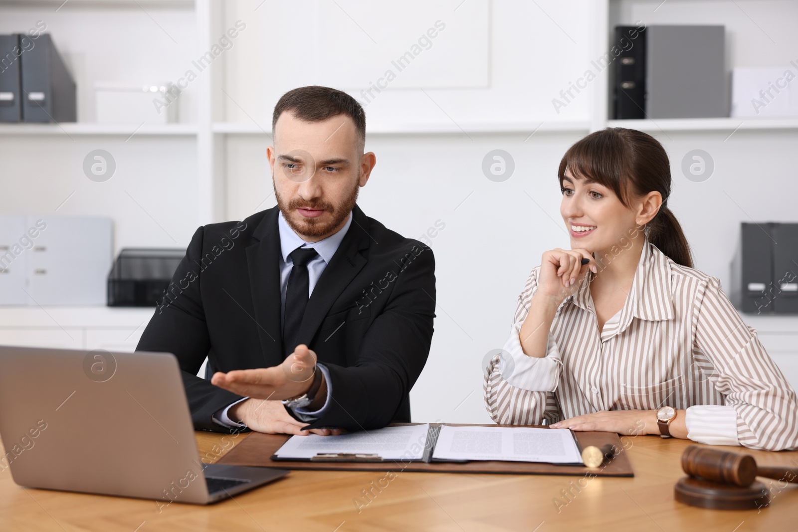 Photo of Woman having meeting with professional notary at wooden desk indoors